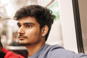 Portrait of young Indian man passenger traveling in the metro. Delhi metro and Public transportation concept. 