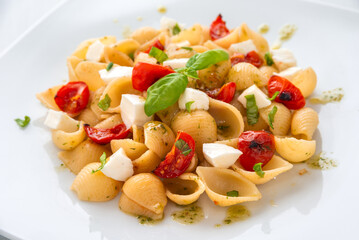 Piatto di pasta alla caprese, con pomodoro, mozzarella, basilico e olio di oliva, cibo italiano 