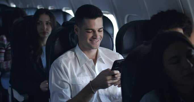 Young man watching phone and chatting with high speed internet technology, happy and carefree during the flight in first class.