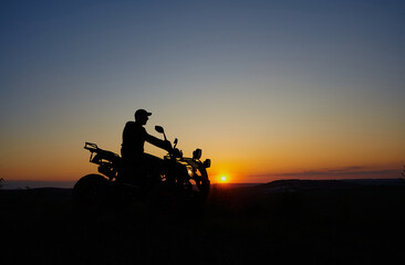 shadow of a biker at sunset, a man travels on a quad bike at sunset on a mountain
