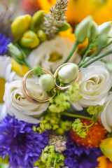 Obraz na płótnie Canvas wedding rings in a colorful flower bouquet from the bride and groom