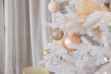 White Christmas tree with pastel colored decoration with balls on fir branches with blurred background.Holiday decoration.Christmas and New Year holidays background