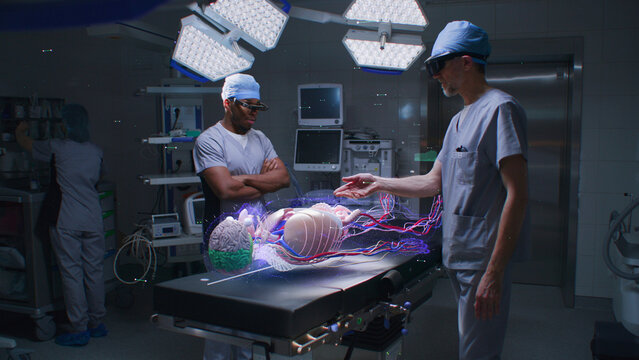 Diverse male surgeons in AR headsets work in operating room using holographic display. 3D graphics of virtual human skeleton, organs and vital signs. AI technology in medicine. Futuristic healthcare.