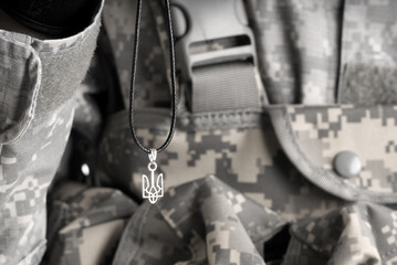 Soldier holding pendant with Ukrainian coat of arms, closeup