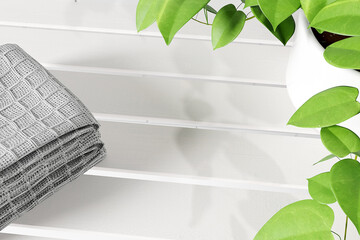 Mockup stack of towels and houseplant on white wooden shelf with place for beauty product promotion, 3d render