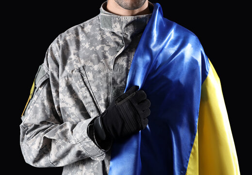 Male soldier with flag of Ukraine on black background