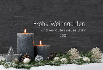 Weihnachtsdekoration mit Kerze,  Tannenästen, Weihnachtsschmuck auf Schnee mit dem Text Frohe...