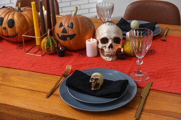 Festive table setting for Halloween celebration with pumpkins, skulls and burning candles