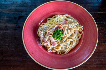 a birds eye view over a bowl of freshly made spaghetti carbonara with grilled bacon.