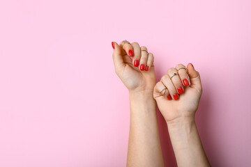 Female hands with stylish red manicure on pink background