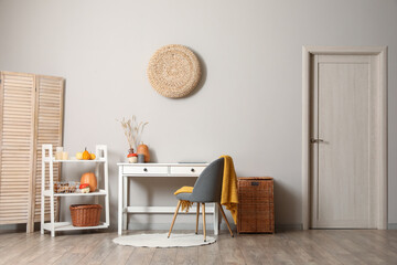 Interior of modern living room with cozy workplace and pumpkins