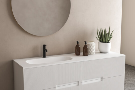 Close up of sink with oval mirror standing in on beige wall , white cabinet with black faucet in minimalist bathroom. Side view.