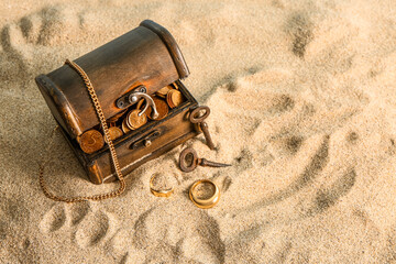 Old chest with treasures and keys on sand