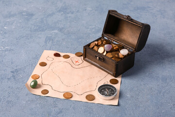 Old chest with treasures, compass and map on blue grunge background © Pixel-Shot
