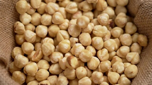 Peeled hazelnut kernels. Shelled filbert nuts falling in slow motion close up on a burlap cloth