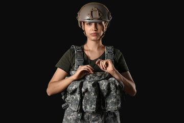 Confident young female soldier in uniform on black background