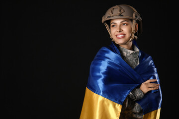 Young female soldier in uniform with flag of Ukraine on black background