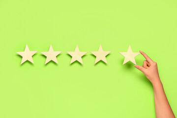 Female hand with five stars rating on green background. Customer experience concept