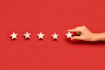 Female hand with five stars rating on red background. Customer experience concept - obrazy, fototapety, plakaty