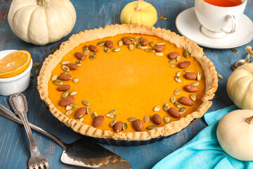 Delicious pumpkin tart with orange, almond and seeds on blue wooden background