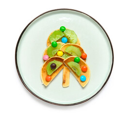 Plate with pancakes in shape of Christmas tree on white background