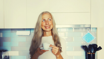 Portrait of happy smiling middle-aged gray-haired woman enjoying hot tasty cup of coffee or tea in...