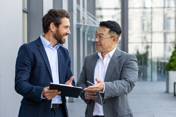 Businessmen, a team of men are standing on the street outside the office, talking and discussing...