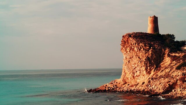 Xarco Tower on coastal cliff, La Vila Joiosa in Alicante province, Spain. Seaside landscape. Tourist attraction.