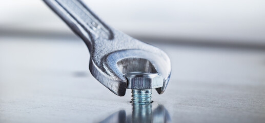 Wrench tightens bolt in steel billet. Spanner, bolt, screw and nuts.