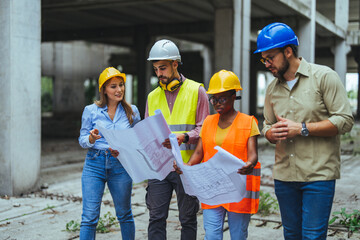 Happy mature engineer discussing the structure of the building with architects colleague at construction site. Engineers wearing safety hardhat having work conversation on the safety of the structure.