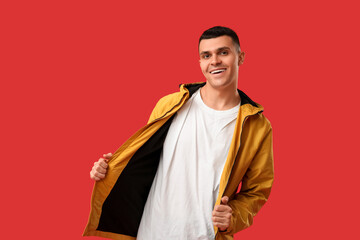 Young man in stylish jacket on red background