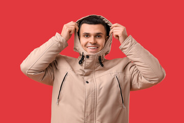 Happy young man in stylish puffer jacket on red background