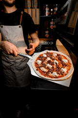 Baking mastery. Chef uses oven shovel to put pizza in the oven.