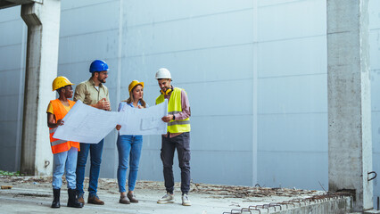 Business, building, teamwork and people concept - group of builders and architects in hardhats with blueprint on construction site. Team of workers conclude an agreement.