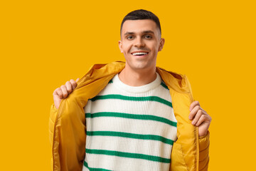 Young man in stylish puffer jacket on yellow background