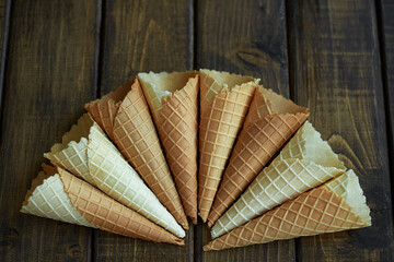 Loose ice cream waffle cones or cornets scattered on a rustic wood surface with copy space in banner format
