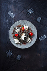 Traditioneller Halloween Tintenfisch Spaghetti mit Dracula Spinnen, Fledermäuse und Bluttropfen Tomaten serviert als Draufsicht in einem Nordic Design Teller 