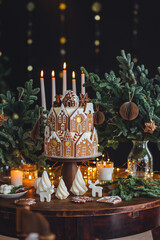 Elegant beautiful handmade gingerbread cookies house with white sugar frosting. Cute magic Christmas village, holiday aesthetics. Cozy home atmosphere, holiday family time. Interior decor, candles