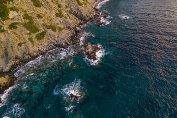 Sea waves crashing of majestic rocks reef and cliffs, aerial view. Drone shot of powerful sea water on coastline