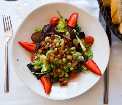 Fresh salad with beans, strawberry, arugula and bacon marinated with soy and honey