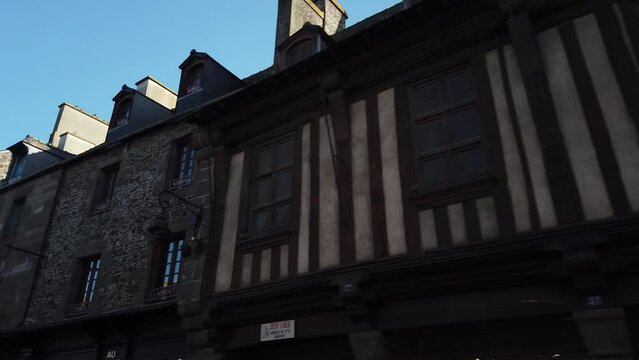 Dol-de-Bretagne, France, October 9, 2023: DOLLY SHOT - The Grande Rue des Stuarts, the main street of the medieval city of Dol-de-Bretagne. Exterior of ancient half-timbered houses.