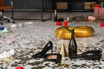 Heels with bottles and confetti on floor in messy office after New Year party, closeup