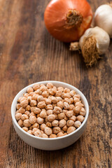 High angle view image of raw chickpeas in a white ceramic bowl on vintage wooden table with copyspace