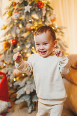 A little boy, 1 year old, decorates the Christmas tree. New Year. Christmas tree.