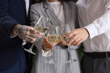 Young colleagues with champagne celebrating New Year at corporate party in office, closeup