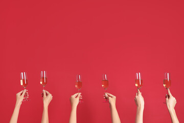 Female hands with glasses of champagne on red background