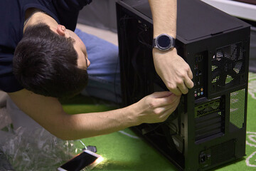 A young man, builds a new computer from components, cable management, the concept of assembling and repairing a computer