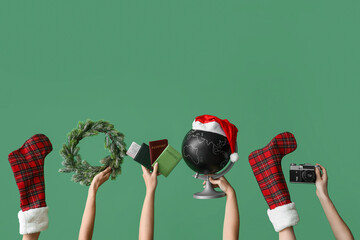 Female hands holding passports with globe, camera and Christmas decor on green background. New year...