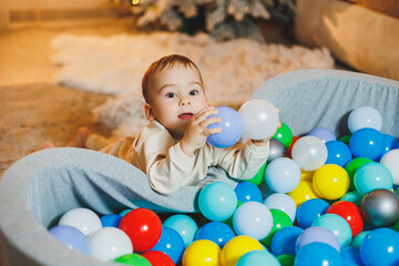 A cute little boy is playing in a pool of plastic balls. Children's dry pool at home.