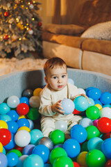 Fototapeta na wymiar A cute little boy is playing in a pool of plastic balls. Children's dry pool at home.
